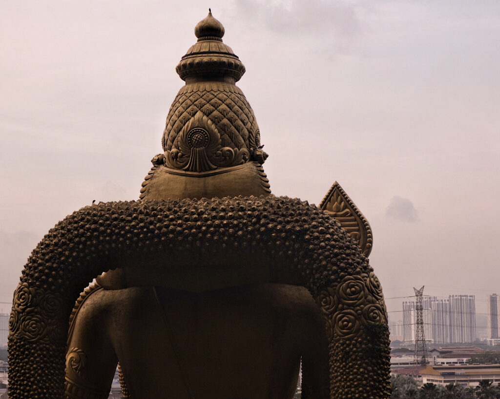 A large golden statue overlooking the city of Kuala Lumpur, showcasing intricate details and a striking presence.