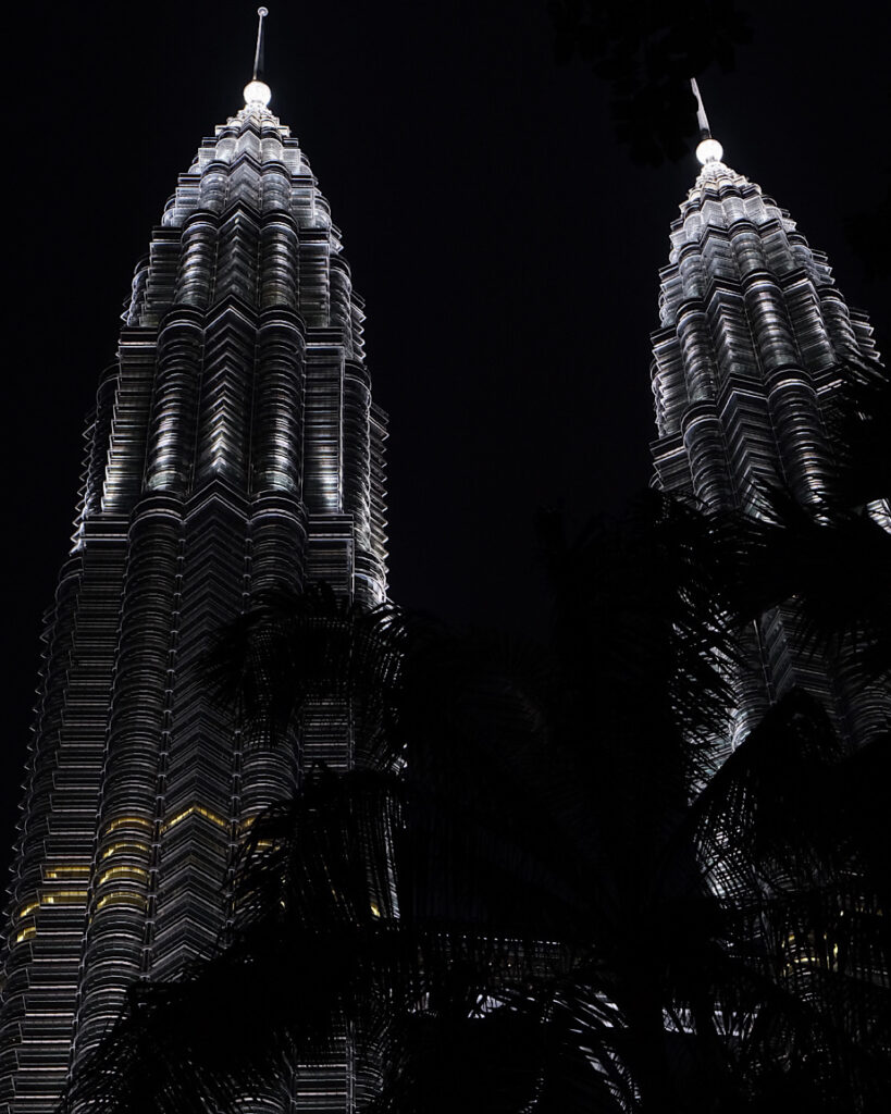 The Petronas Twin Towers illuminated at night, showcasing their stunning architecture against a dark sky.