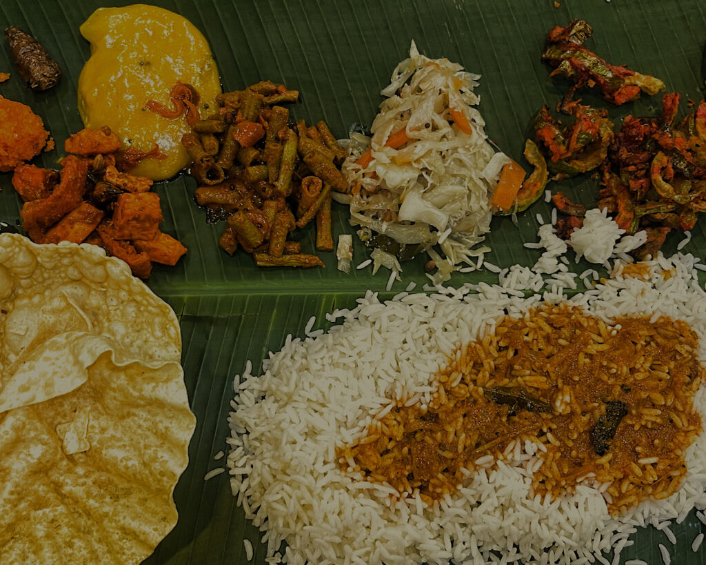 A traditional Indian dish served on a banana leaf with a variety of spices, rice and poppadom.