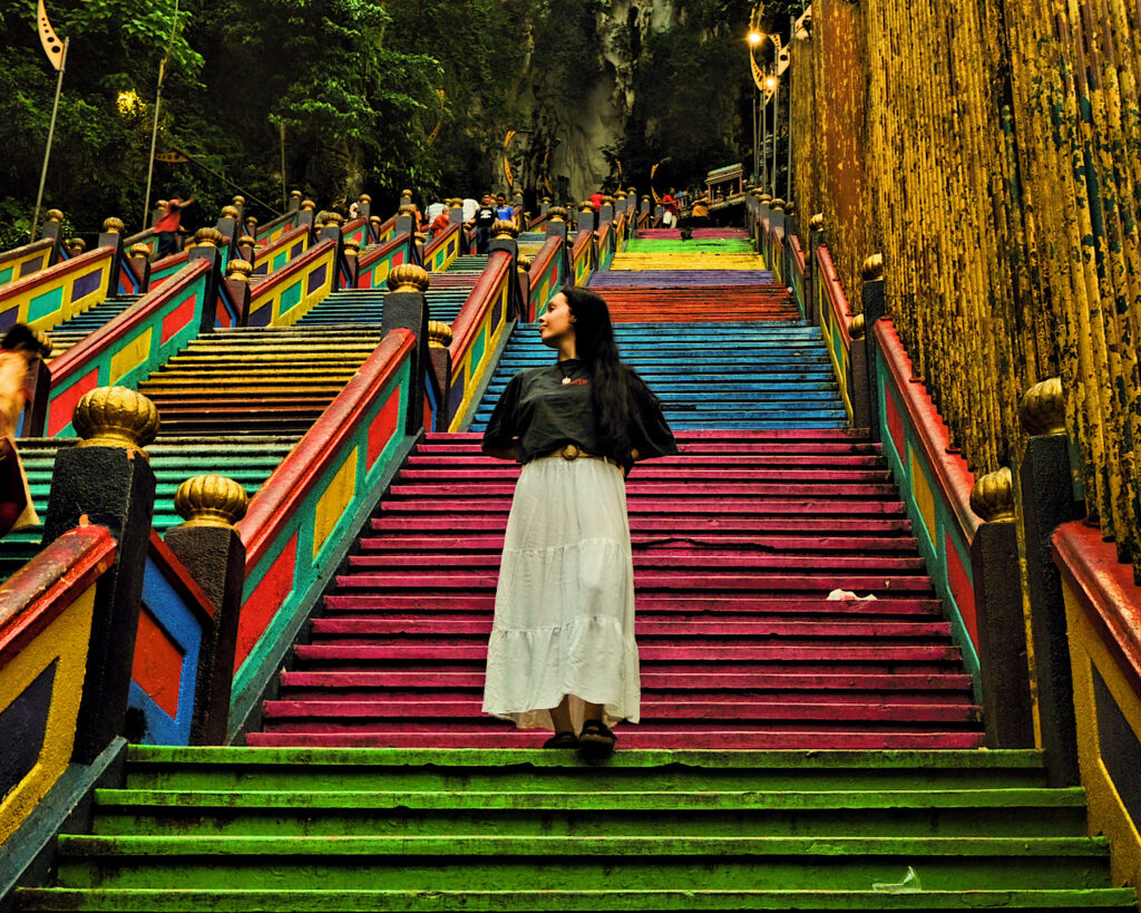 Emily, author of Backpacking Junkie, walking down colourful steps at a temple in Kuala Lumpur, Malaysia.